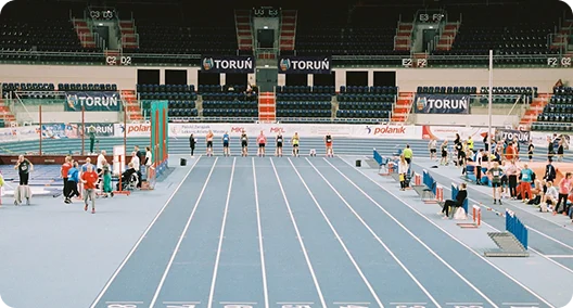 Um atleta de salto em comprimento atingindo o seu ponto mais alto no ar acima da caixa de areia durante um campeonato nacional de atletismo